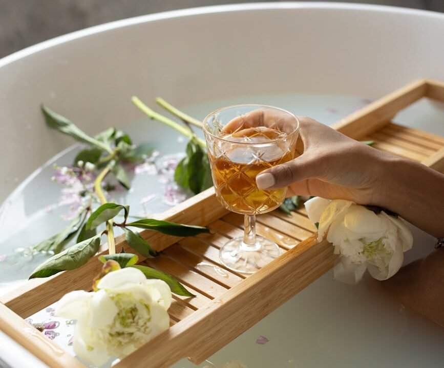 woman with wineglass and flowers in bathtub